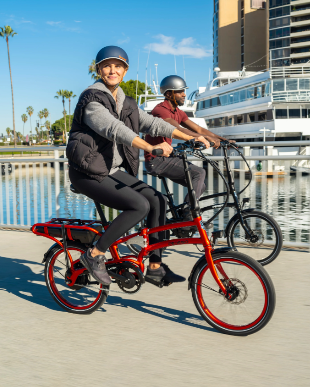 Happy riders on two Pedego Latch V2 folding e-bikes with 20-inch tires and rear rack.